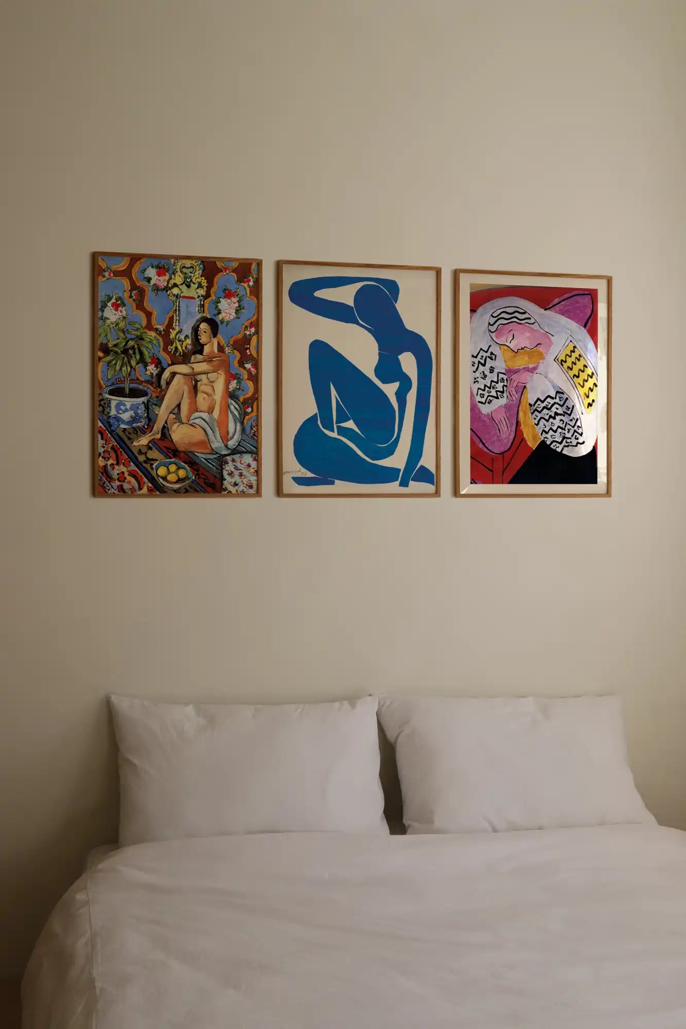 Bed met drie ingelijste kunstafdrukken.