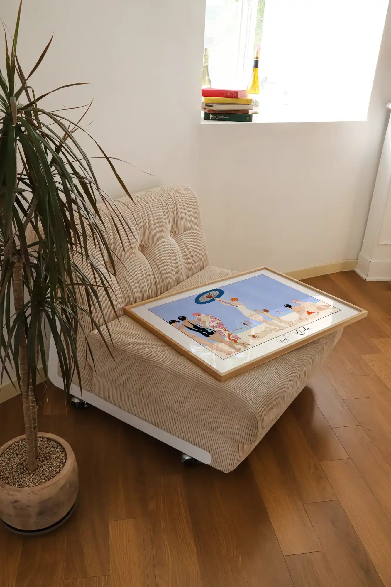 Geknoopte beige stoel met ingelijste kunst.